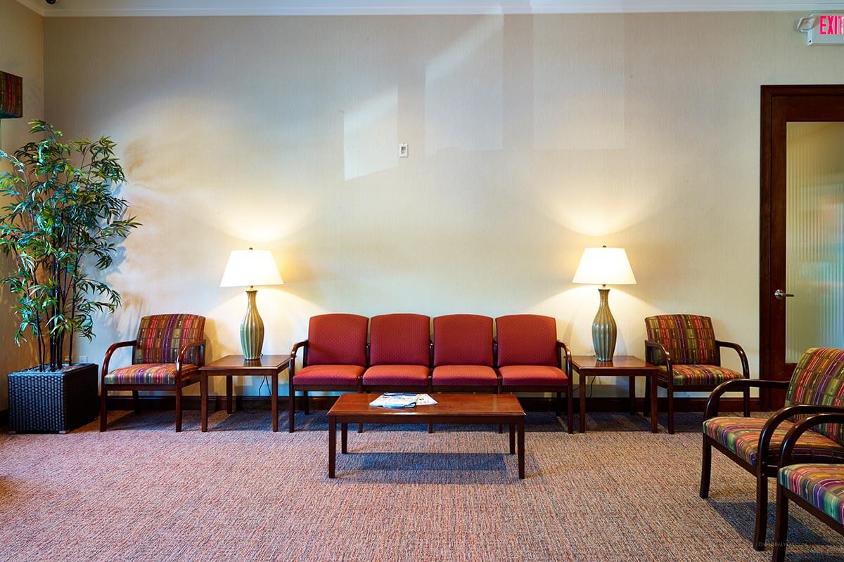 dental waiting room with colorful chairs, a coffee table, two end tables with tall lamps
