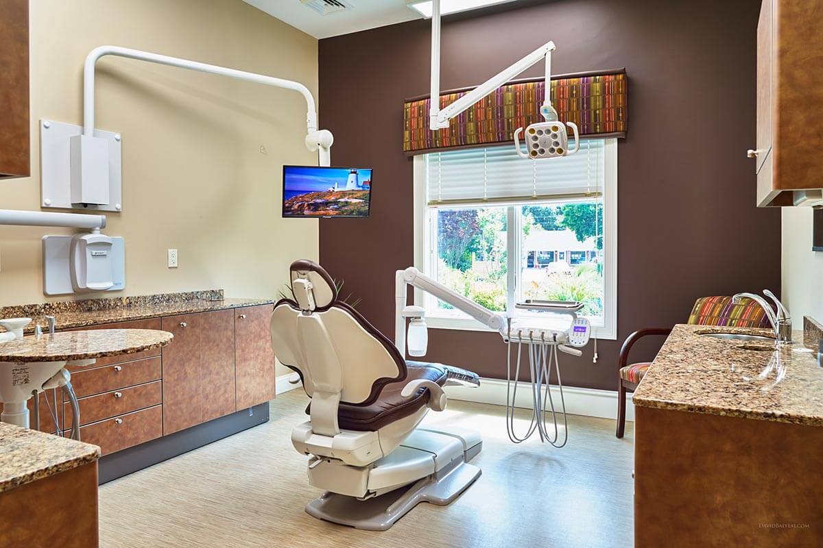 dental exam room with brown wall and large window and flat screen monitor