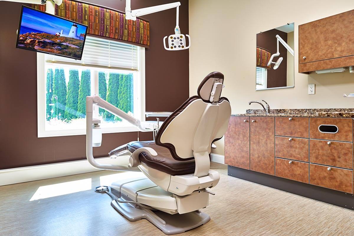 dental exam room with brown wall and large window and brown cabinets