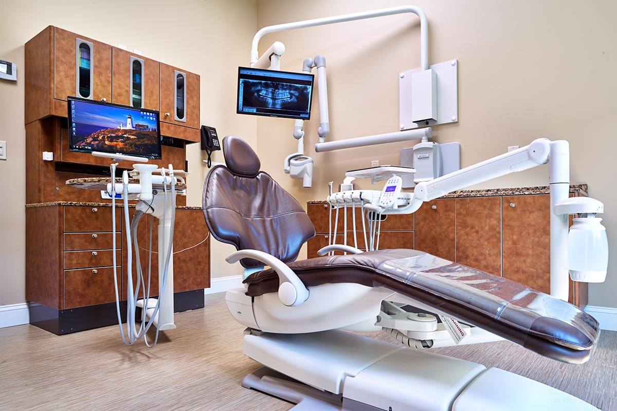 brown dental exam chair in exam room with brown cabinets