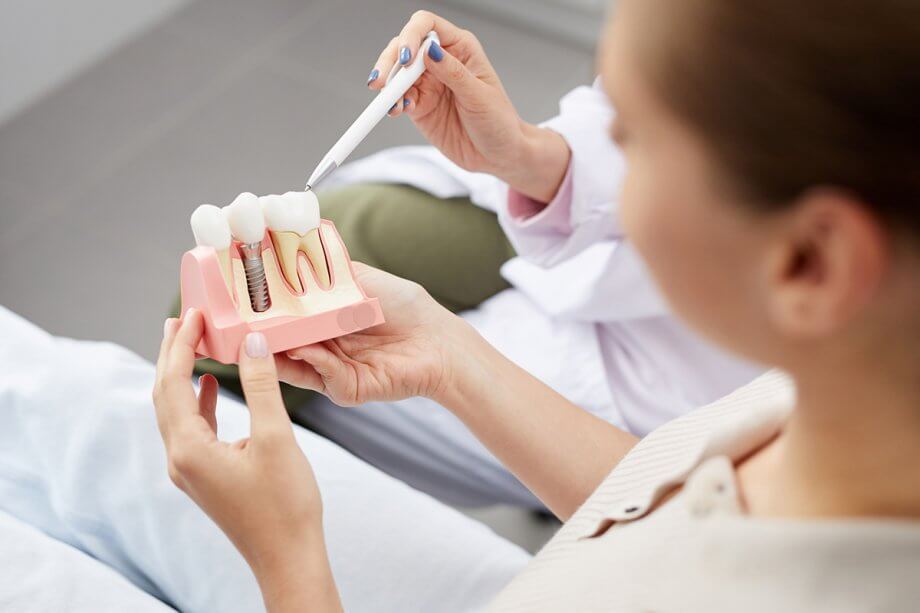 dental patient examines a model of a dental implant and crown