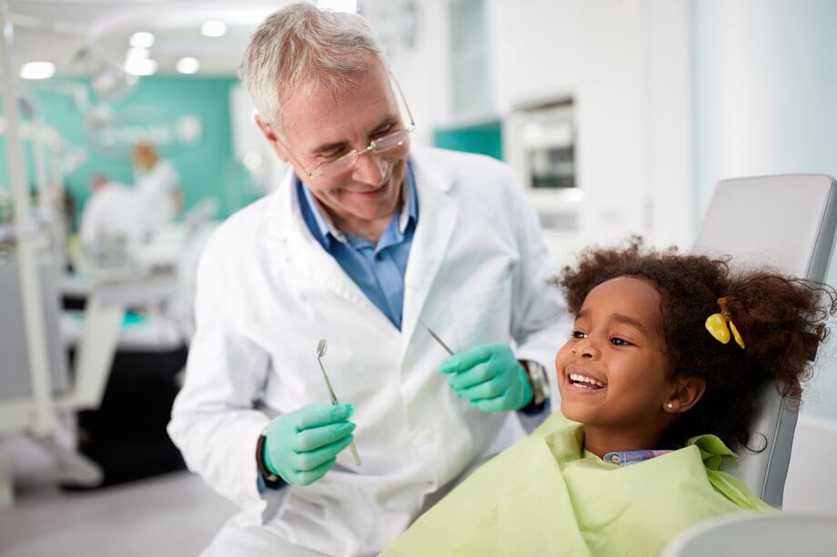 dentist examining young, smiling girl